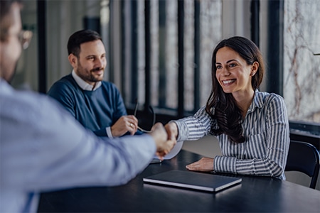 Smiling woman shaking hands with clients in the office