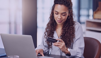 Female holding a credit to make an online payment using laptop